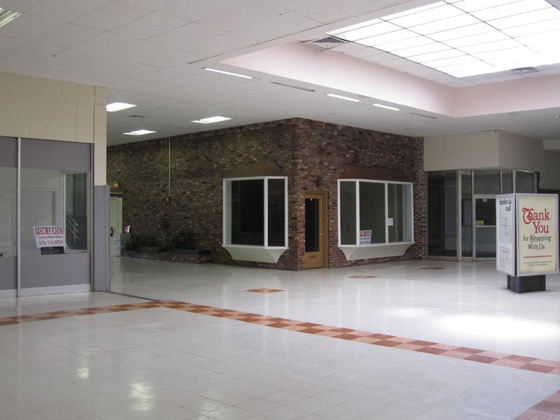 Abandoned dead mall interior frozen in time with empty storefronts and retro 80s signage