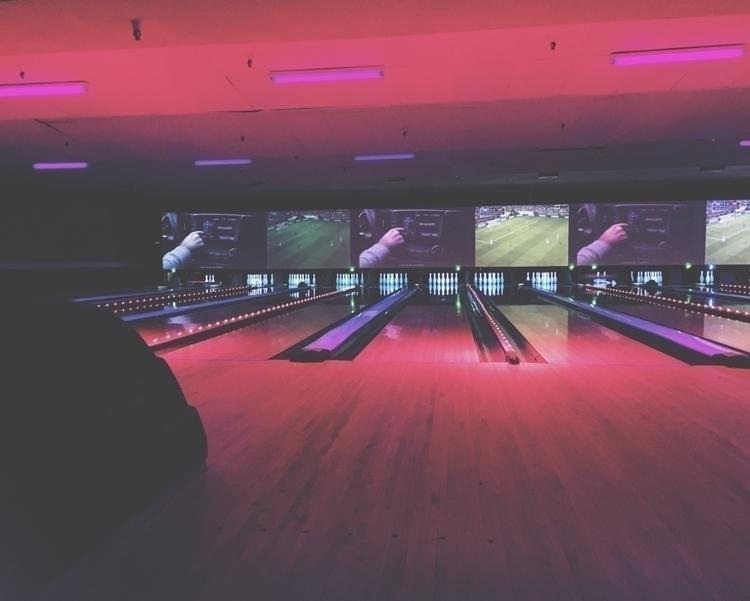 Retro 1990s bowling alley interior with a futuristic mural embodying vaporwave aesthetics
