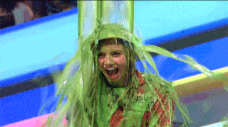 Celebrity getting doused in iconic green Nickelodeon slime on a retro 90s game show stage